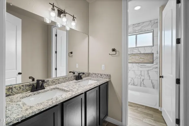 a bathroom with a granite countertop sink a mirror and a shower