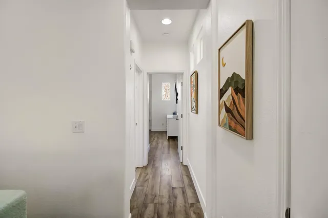 a view of a hallway with wooden floor and a bathroom