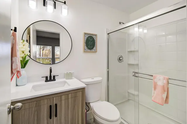 a bathroom with a sink a mirror a toilet and shower