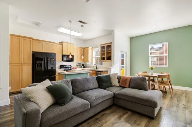 a living room with stainless steel appliances furniture and a kitchen view