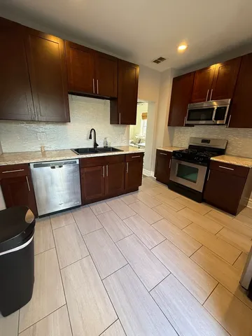 a large kitchen with stainless steel appliances wooden cabinets and a stove top oven