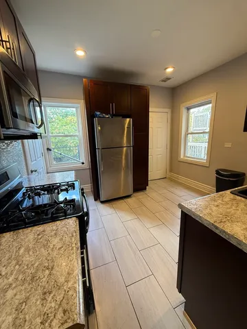 a kitchen with kitchen island granite countertop a stove and a refrigerator