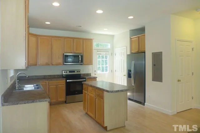 a kitchen with granite countertop a refrigerator and a stove top oven