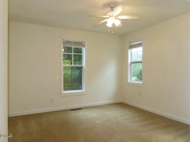 an empty room with a window and a fan