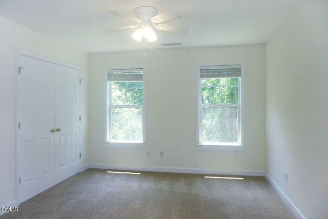 an empty room with windows and fan