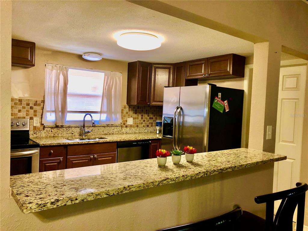 7537 Jasmine Boulevard Port Richey, FL 34668 - Photo 11 of 15 a kitchen with granite countertop a sink and a refrigerator