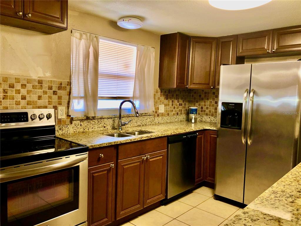 7537 Jasmine Boulevard Port Richey, FL 34668 - Photo 2 of 15 a kitchen with stainless steel appliances granite countertop a stove a refrigerator and a sink