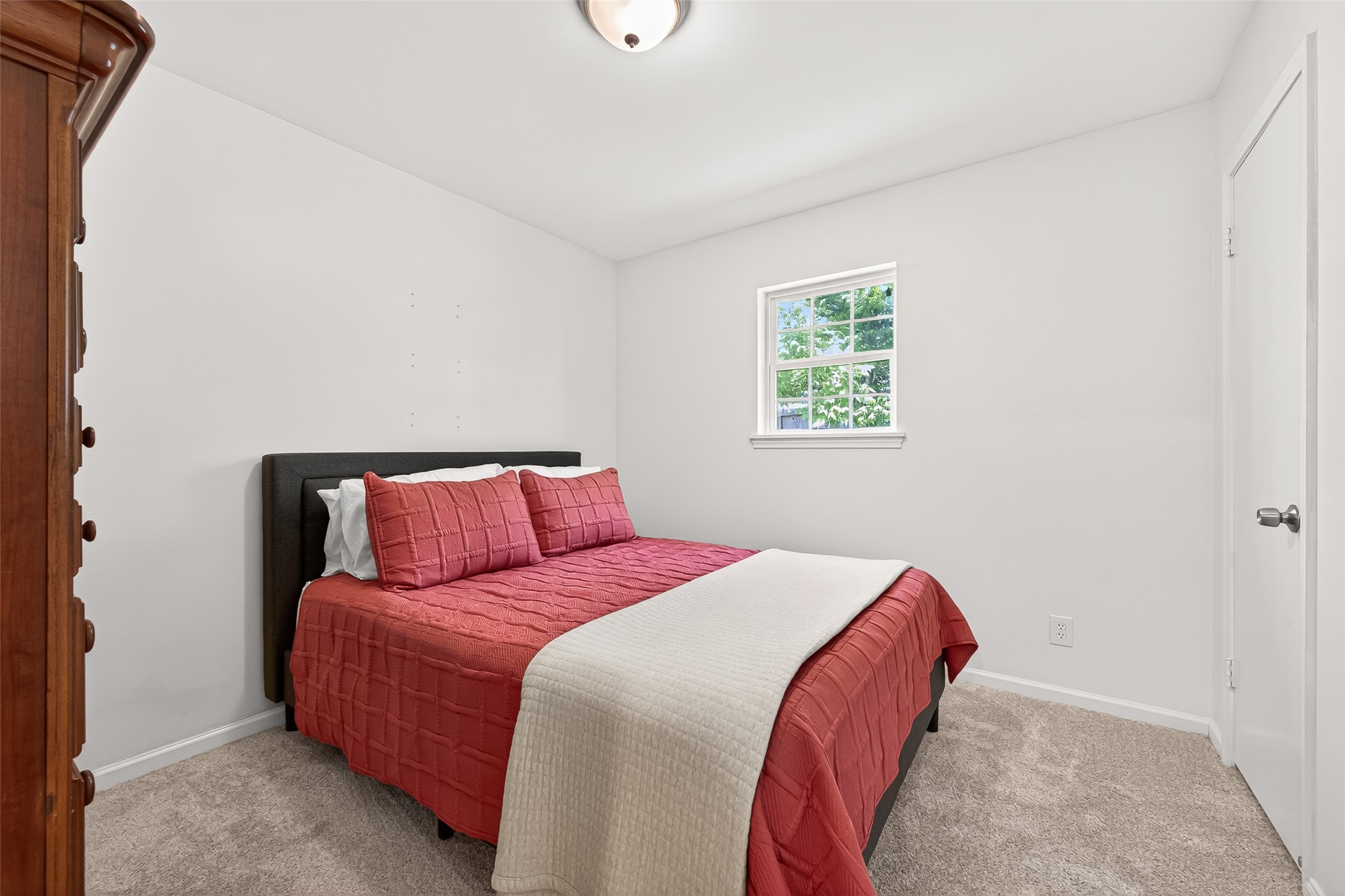 2610 Teague Road Houston, TX 77080 - Photo 40 of 49 Secondary bedroom with a soft, neutral color palette. A window allows natural light to brighten the space, complemented by carpeted flooring and simple decor.