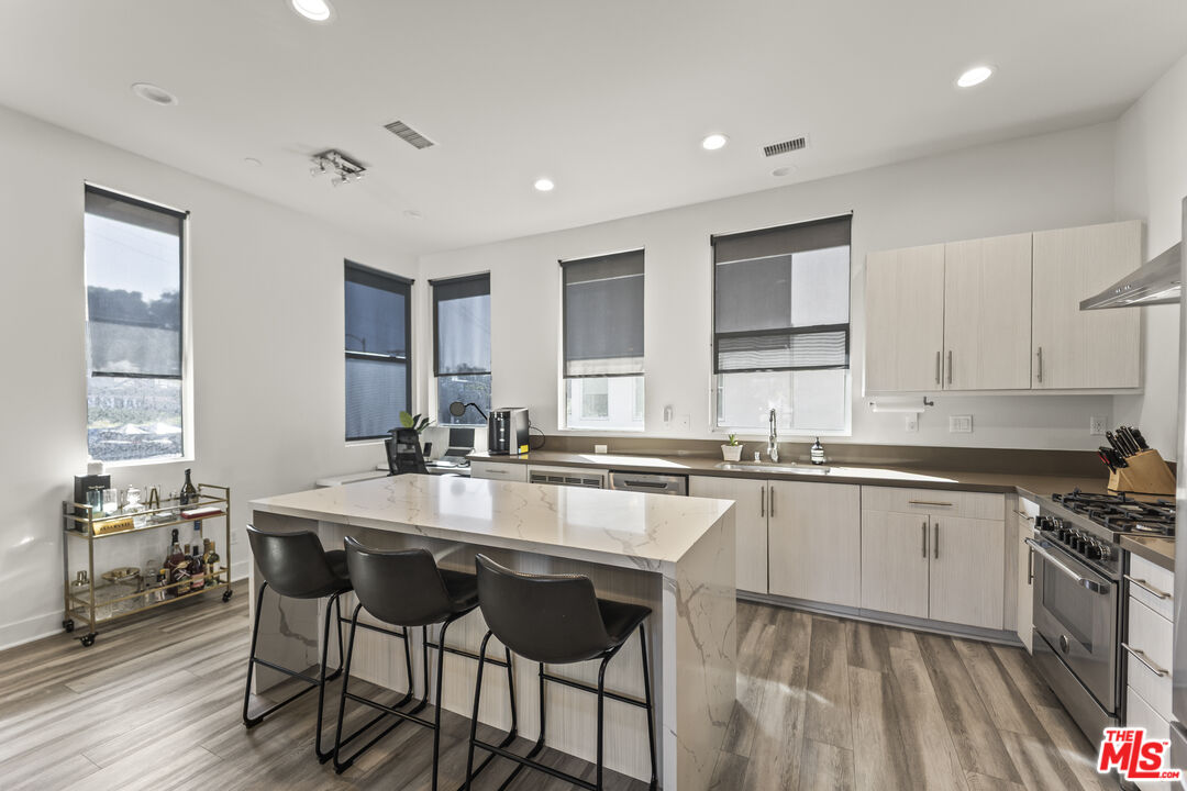 a large kitchen with granite countertop a island in the center a sink a window stainless steel appliances and cabinets