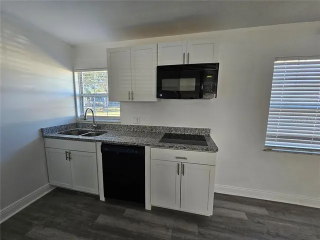 a kitchen with granite countertop white cabinets and black appliances