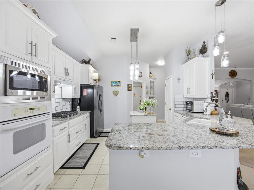 321 Niki Road Paradise, TX 76073 - Photo 12 of 40 a kitchen with granite countertop a sink stainless steel appliances and white cabinets