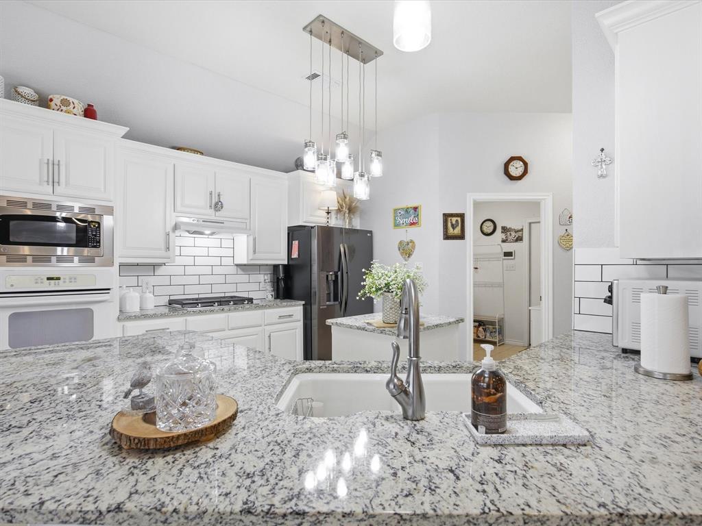 321 Niki Road Paradise, TX 76073 - Photo 13 of 40 a kitchen with stainless steel appliances granite countertop a sink a stove and a refrigerator