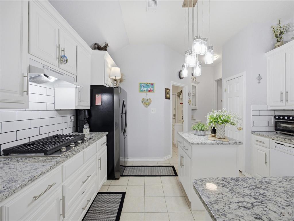 321 Niki Road Paradise, TX 76073 - Photo 14 of 40 a kitchen with stainless steel appliances kitchen island granite countertop a refrigerator a stove a sink dishwasher and white cabinets with wooden floor