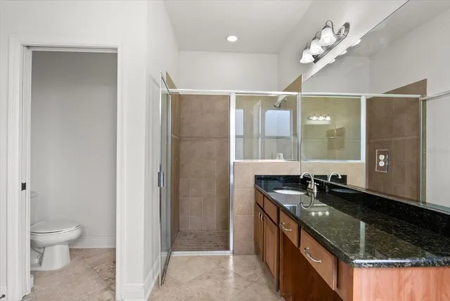 a bathroom with a granite countertop sink a toilet and a mirror