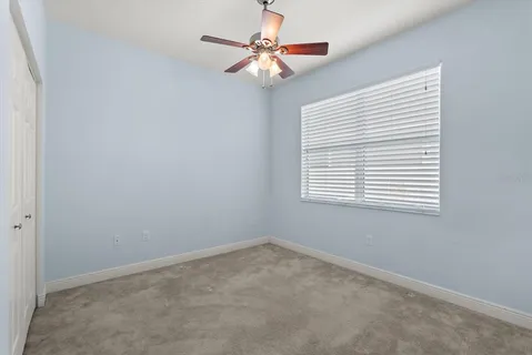 an empty room with a window and a fan