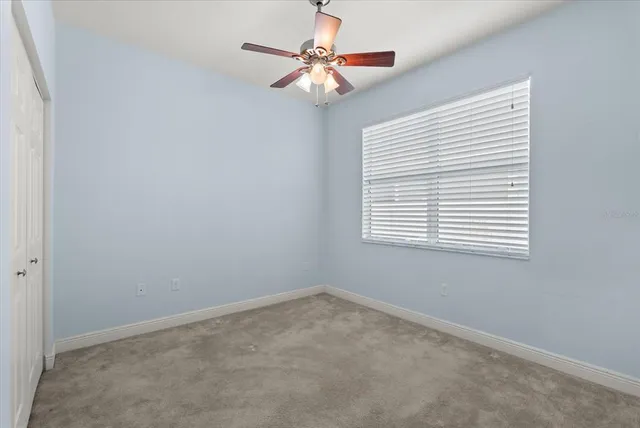 an empty room with a window and a fan