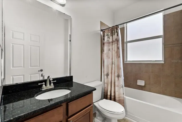 a bathroom with a granite countertop sink toilet and shower