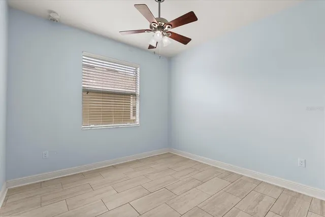 an empty room with a window and a fan