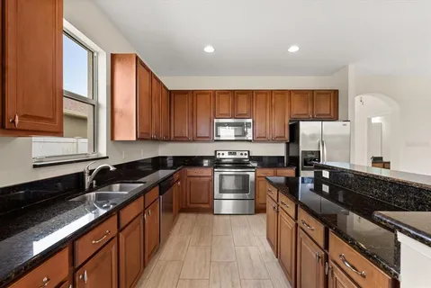 a kitchen with granite countertop wooden cabinets a stove top oven and stainless steel appliances