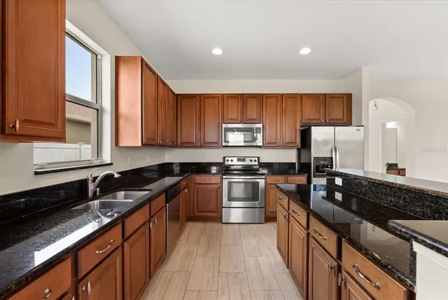 a kitchen with granite countertop wooden cabinets a stove top oven and stainless steel appliances