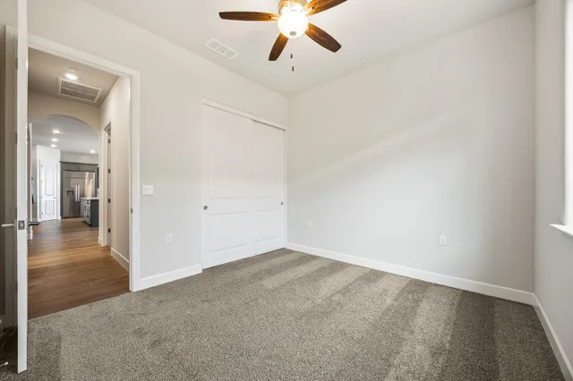 an empty room and chandelier fan in hallway
