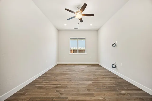 an empty room with wooden floor and a ceiling fan