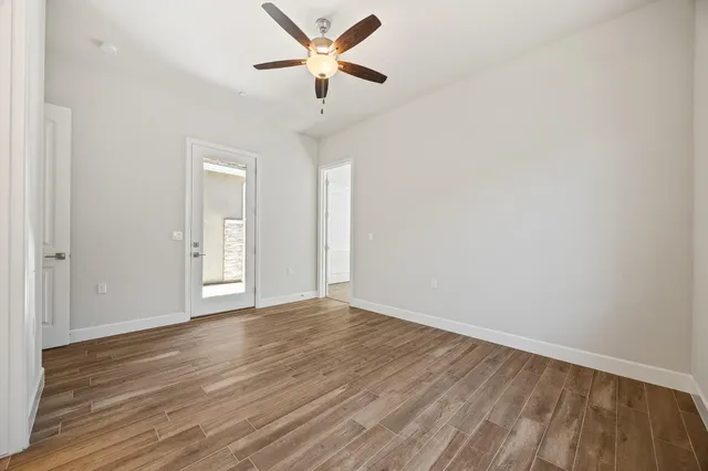 an empty room with wooden floor and a ceiling fan
