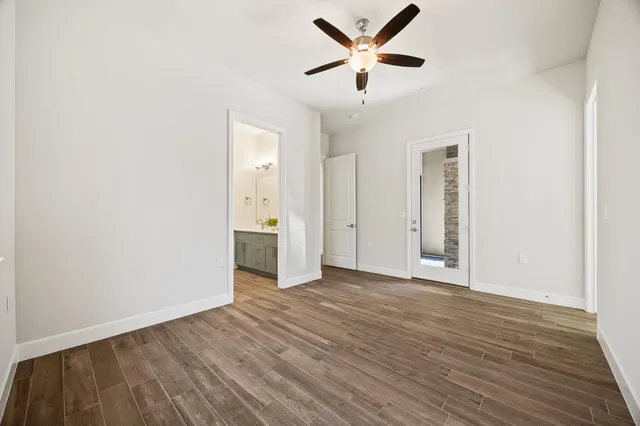 an empty room with wooden floor and a ceiling fan