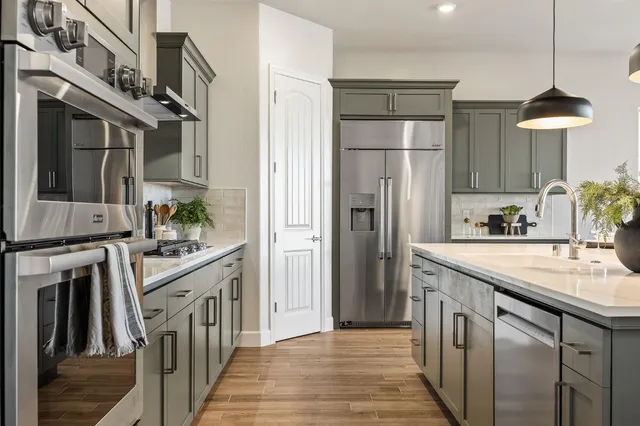 a kitchen with stainless steel appliances granite countertop a refrigerator a stove and a sink with wooden floor