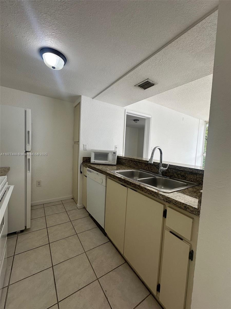 7125 Northwest 186th Street, Unit B208 Hialeah, FL 33015 - Photo 2 of 10 a kitchen with stainless steel appliances granite countertop a sink and a stove top oven