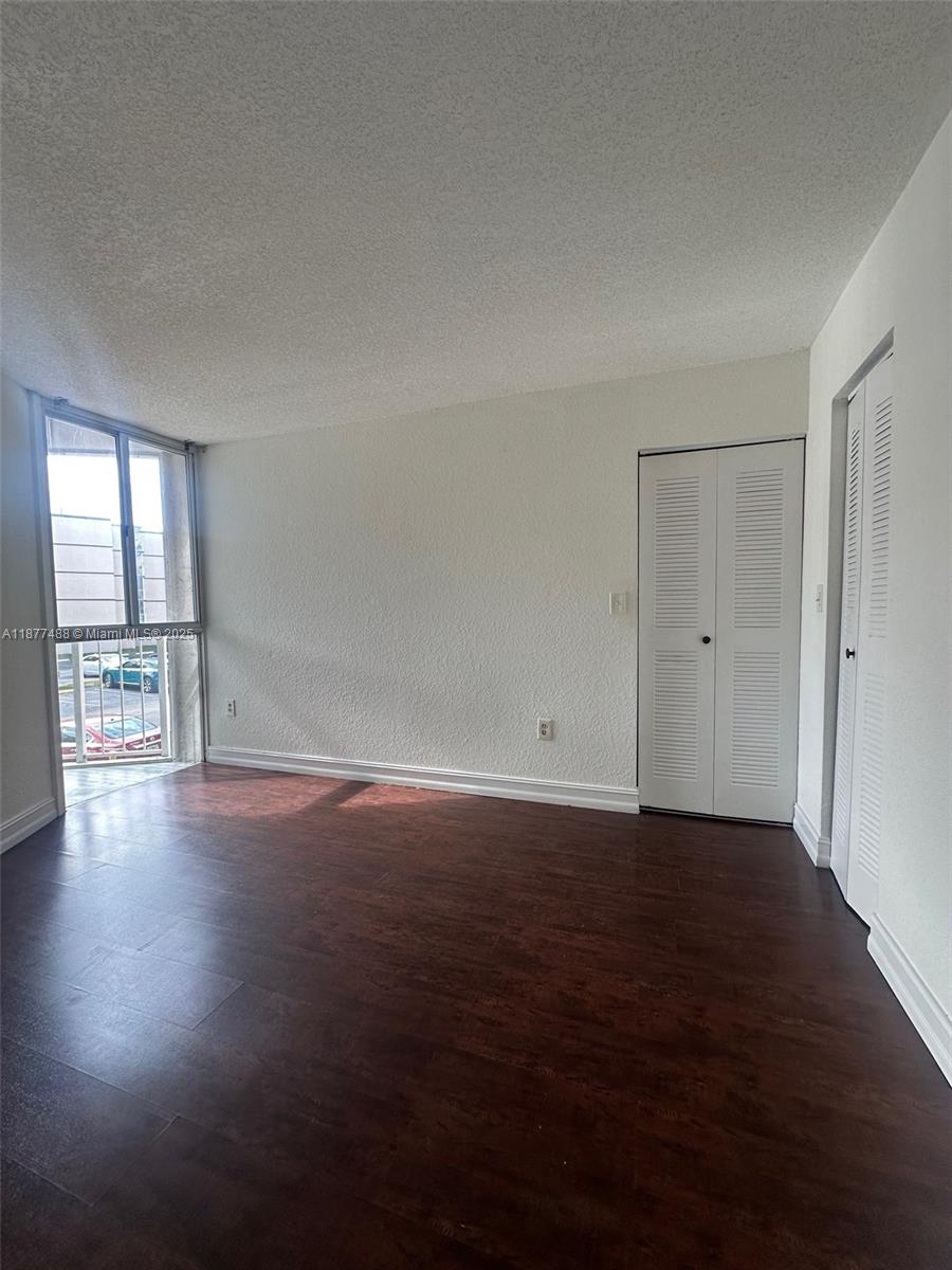 7125 Northwest 186th Street, Unit B208 Hialeah, FL 33015 - Photo 6 of 10 an empty room with wooden floor and windows