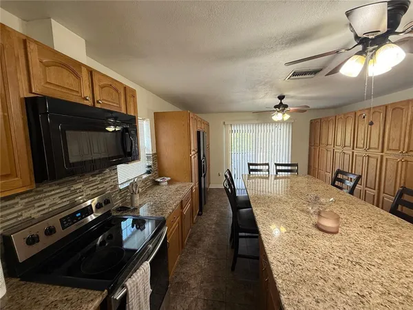 a large kitchen with a stove a sink and a microwave