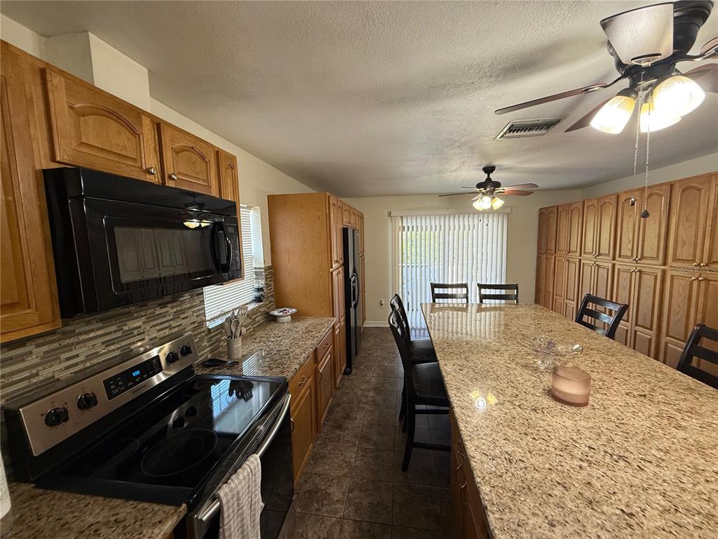 7223 Tarrytown Drive Spring Hill, FL 34606 - Photo 6 of 27 a large kitchen with a stove a sink and a microwave