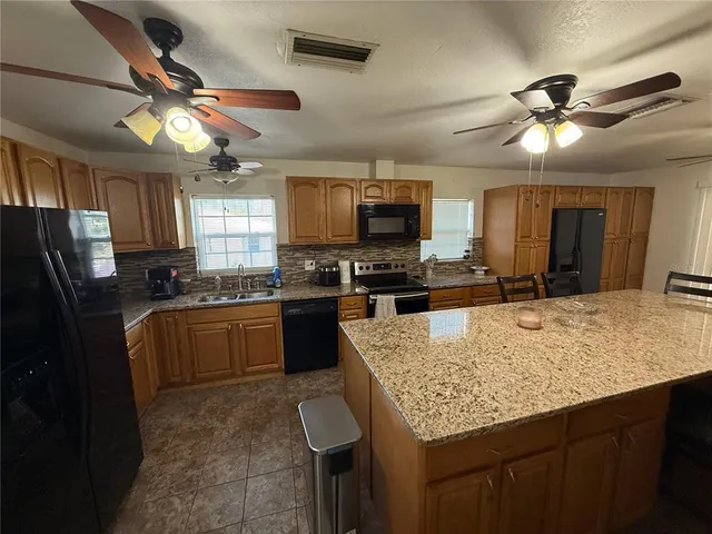 a kitchen with stainless steel appliances granite countertop a sink a stove and a refrigerator