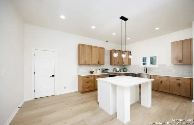 a kitchen with a stove a sink a counter top space and cabinets
