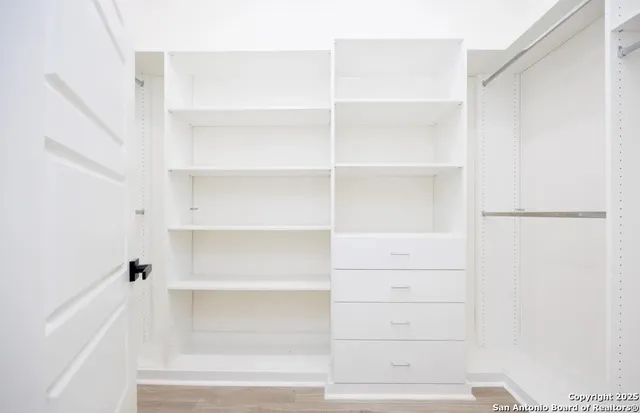 a view of walk in closet with empty racks
