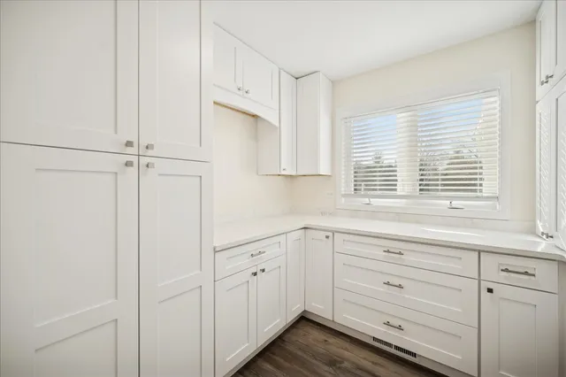 a kitchen with white cabinets and window