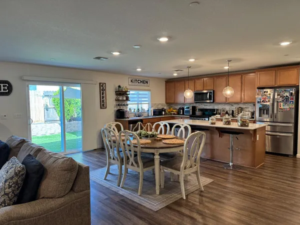 a kitchen with stainless steel appliances granite countertop a stove a refrigerator a kitchen island with a dining table and chairs