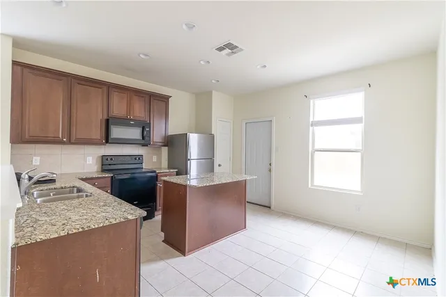 a kitchen with stainless steel appliances granite countertop a refrigerator a stove a sink a microwave and a refrigerator