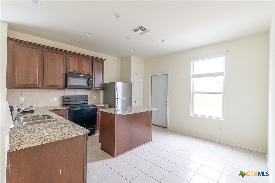 145 Miracle Drive Jarrell, TX 76537 - Photo 8 of 23 a kitchen with stainless steel appliances granite countertop a stove a sink and a refrigerator