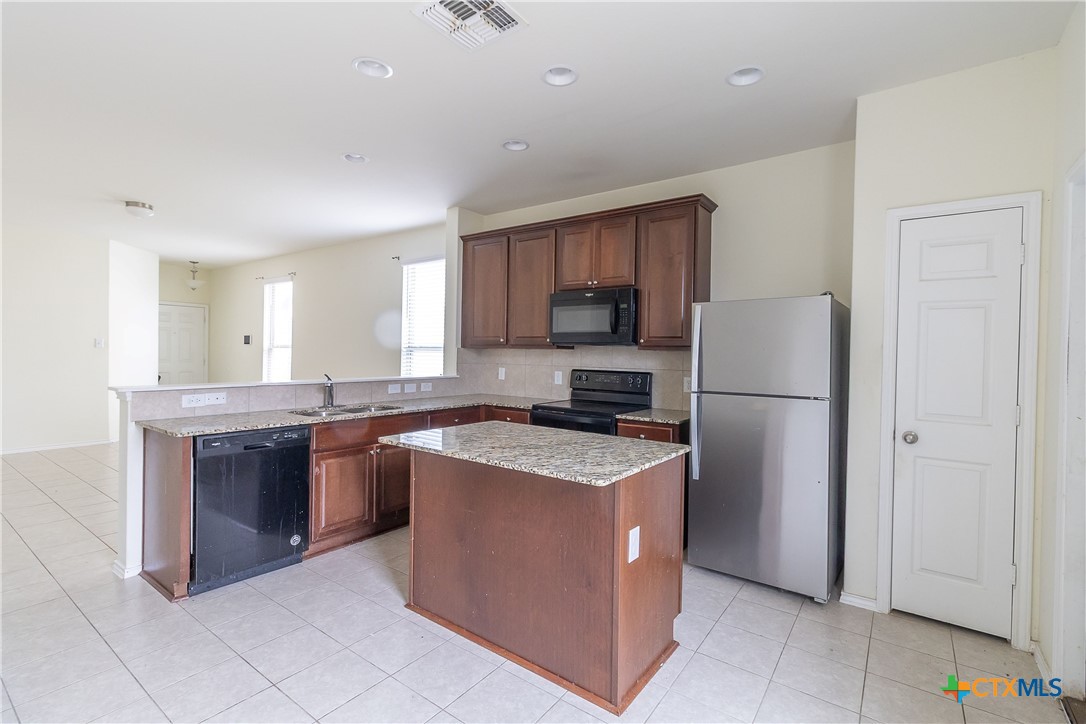 145 Miracle Drive Jarrell, TX 76537 - Photo 9 of 23 a kitchen with stainless steel appliances granite countertop a refrigerator a stove a sink a microwave and a refrigerator