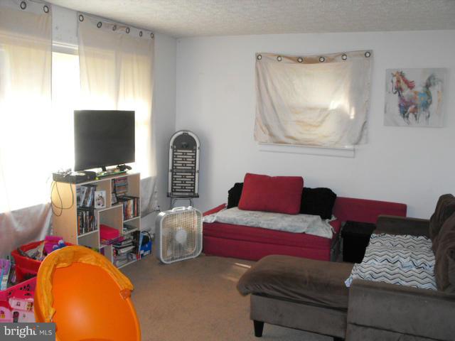 245 Tate Road Prince Frederick, MD 20678 - Photo 2 of 15 a living room with furniture a flat screen tv and gym equipment