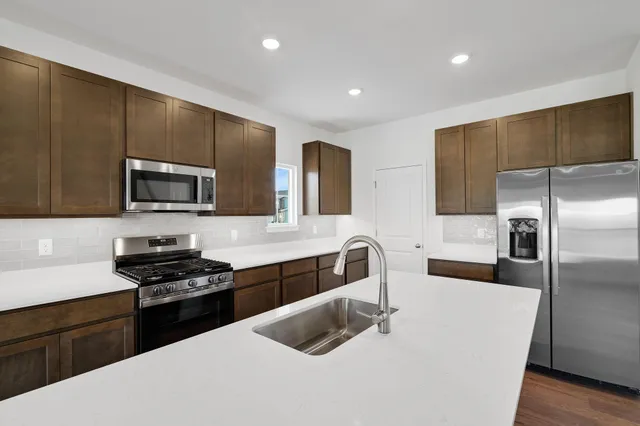 a kitchen with granite countertop a refrigerator and a stove top oven
