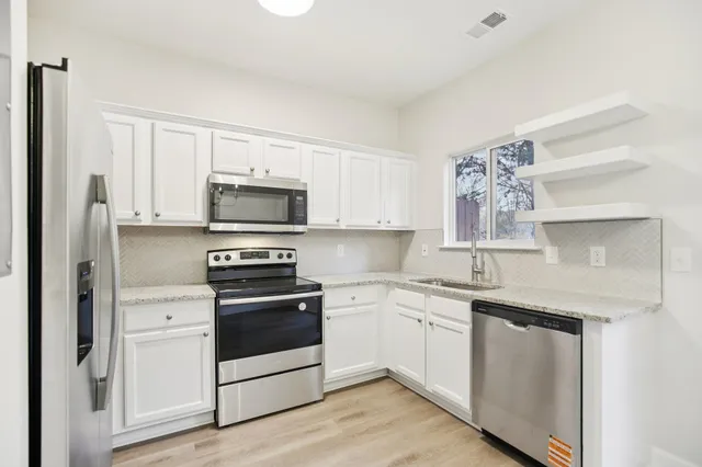 a kitchen with white cabinets stainless steel appliances and sink