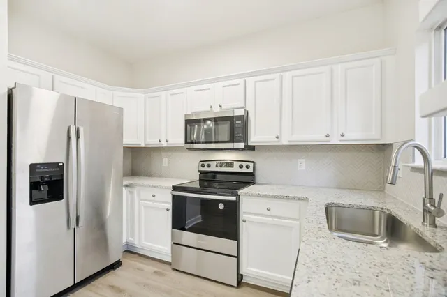 a kitchen with stainless steel appliances white cabinets and a refrigerator