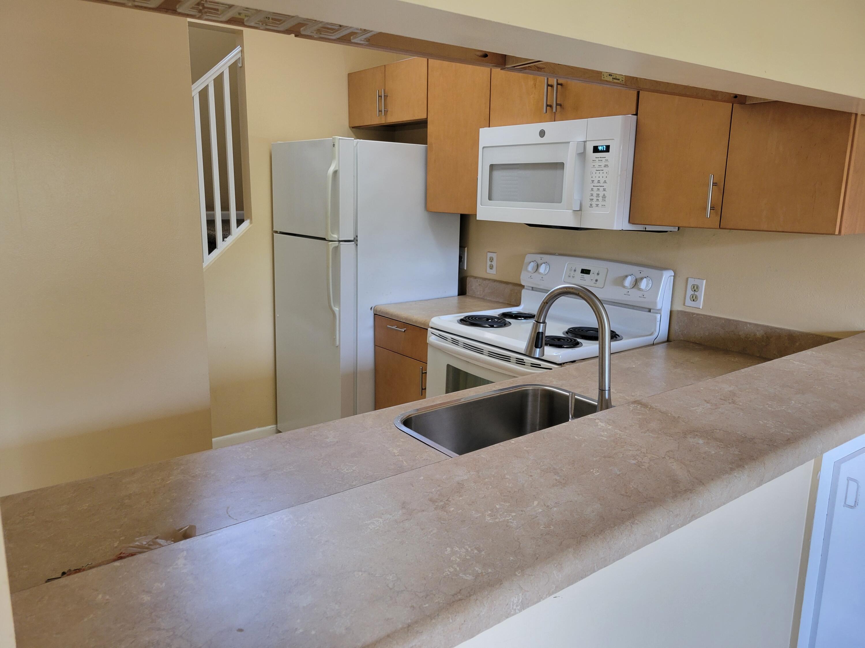 1112 Coral Club Drive, Unit 1112 Coral Springs, FL 33071 - Photo 5 of 16 a kitchen with stainless steel appliances granite countertop a refrigerator and a stove