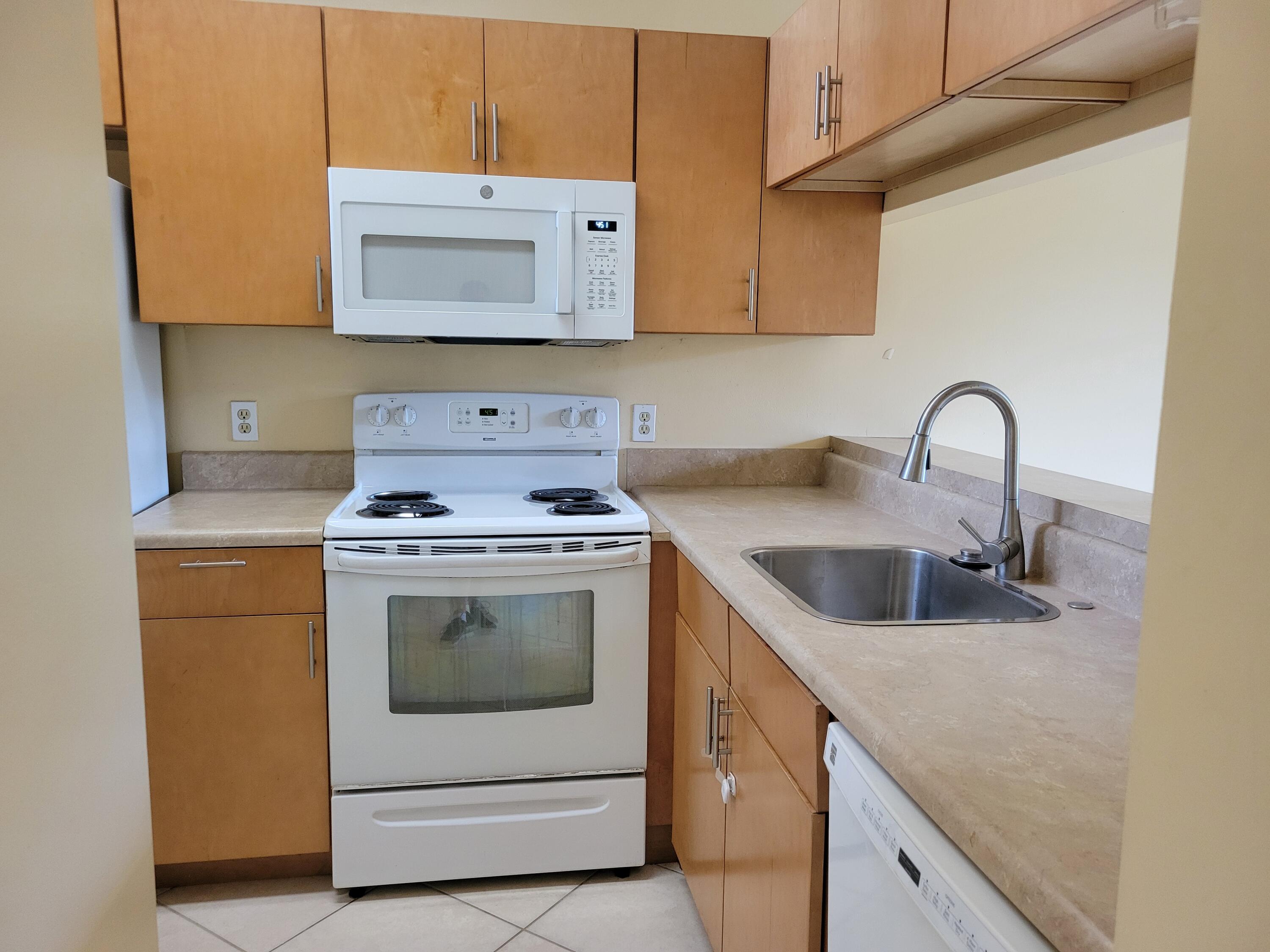 1112 Coral Club Drive, Unit 1112 Coral Springs, FL 33071 - Photo 6 of 16 a kitchen with granite countertop a sink a stove and cabinets