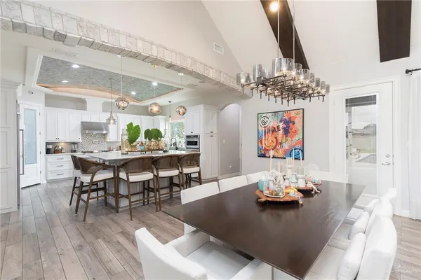 a view of a dining room and livingroom with furniture wooden floor a rug a painting and a chandelier