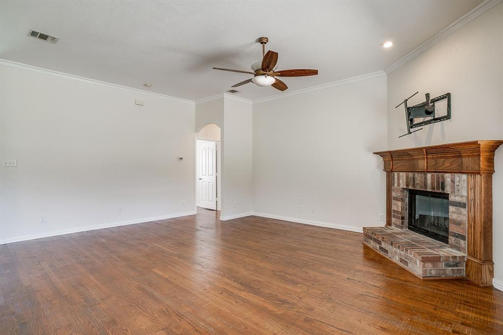 209 Cooperstown Drive Springtown, TX 76082 - Photo 11 of 40 Unfurnished living room with ornamental molding, arched walkways, dark wood-type flooring, a fireplace, and ceiling fan