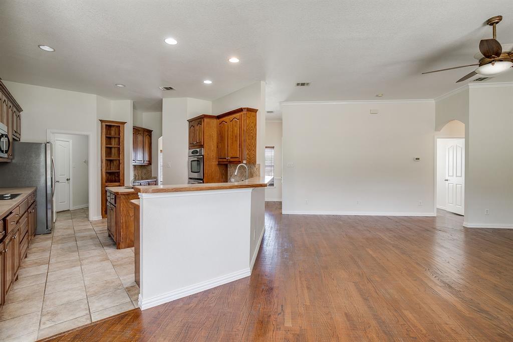 209 Cooperstown Drive Springtown, TX 76082 - Photo 40 of 40 Kitchen with brown cabinetry, open floor plan, arched walkways, light wood-style flooring, and a ceiling fan